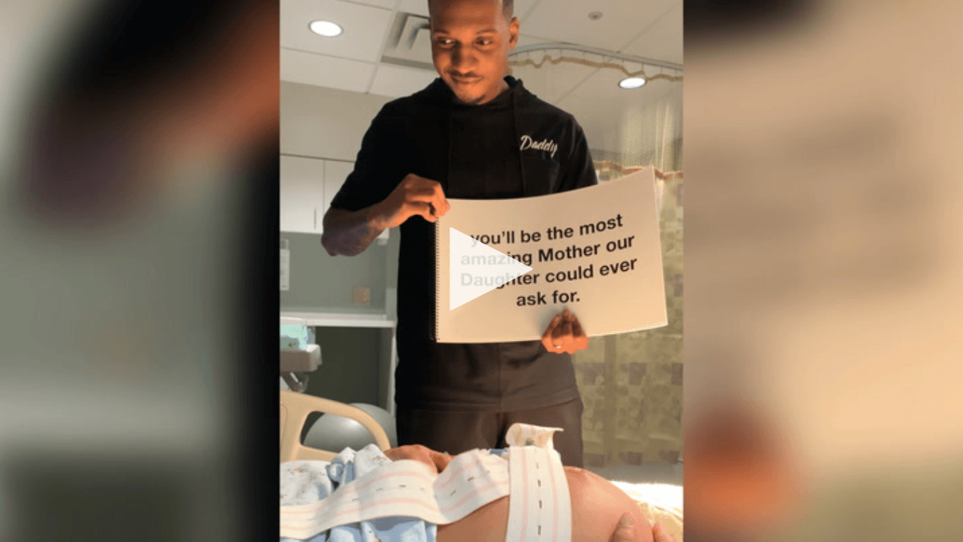 video screenshot of dad holding up supportive signs to mom in labor