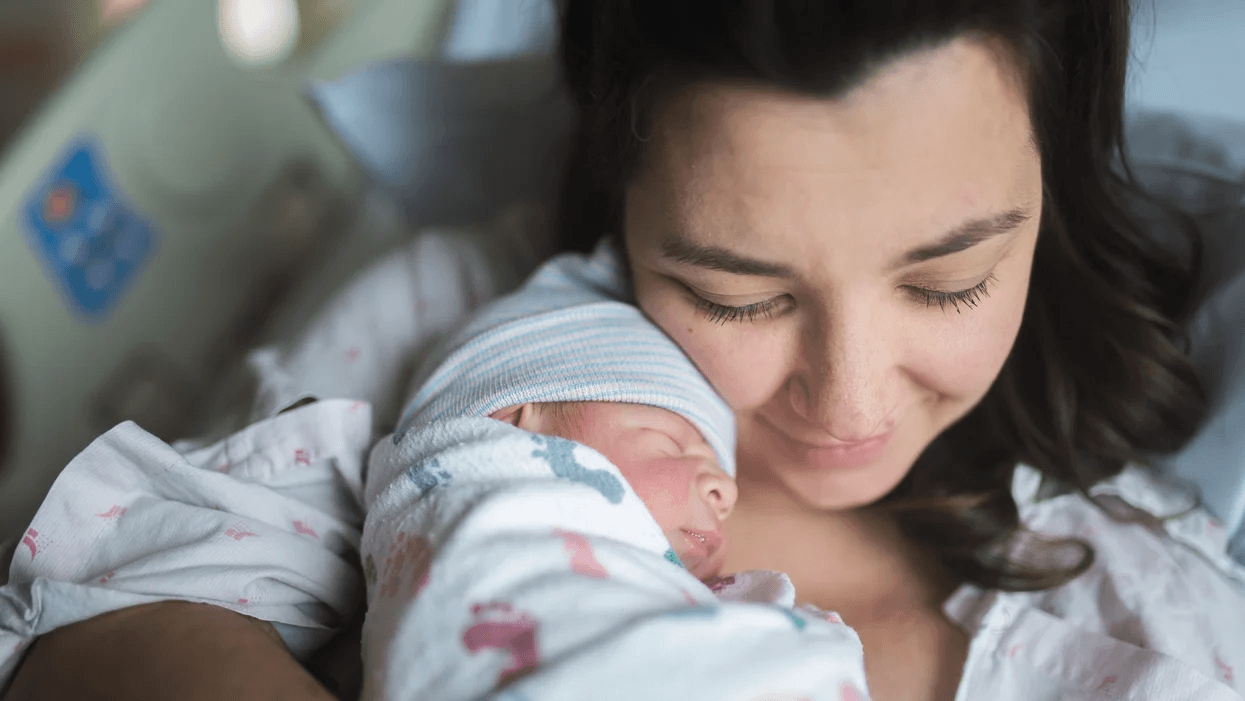 mom snuggling newborn in a hospital bed