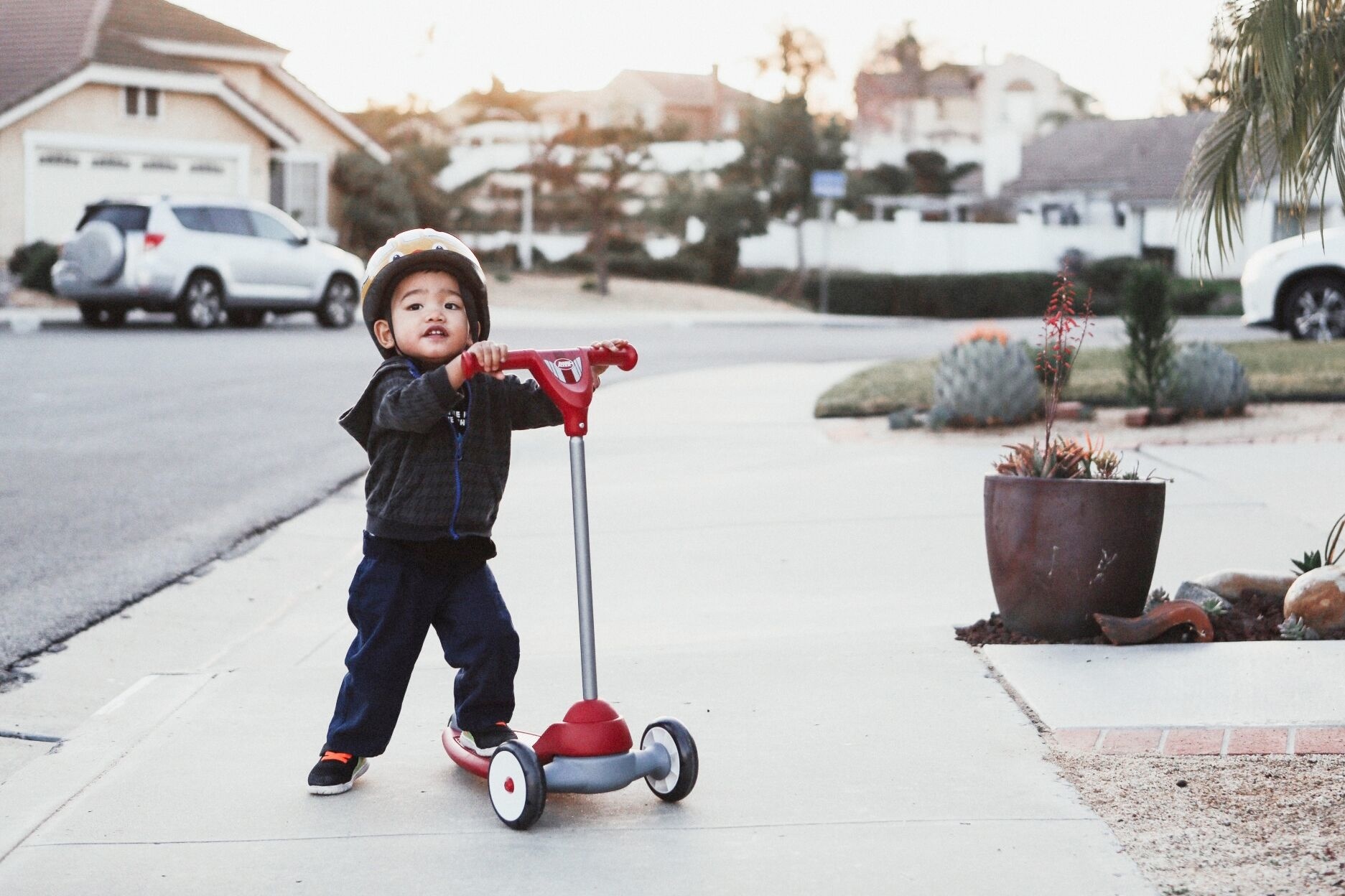 child riding on a scooter outside - benefits of outdoor play for kids