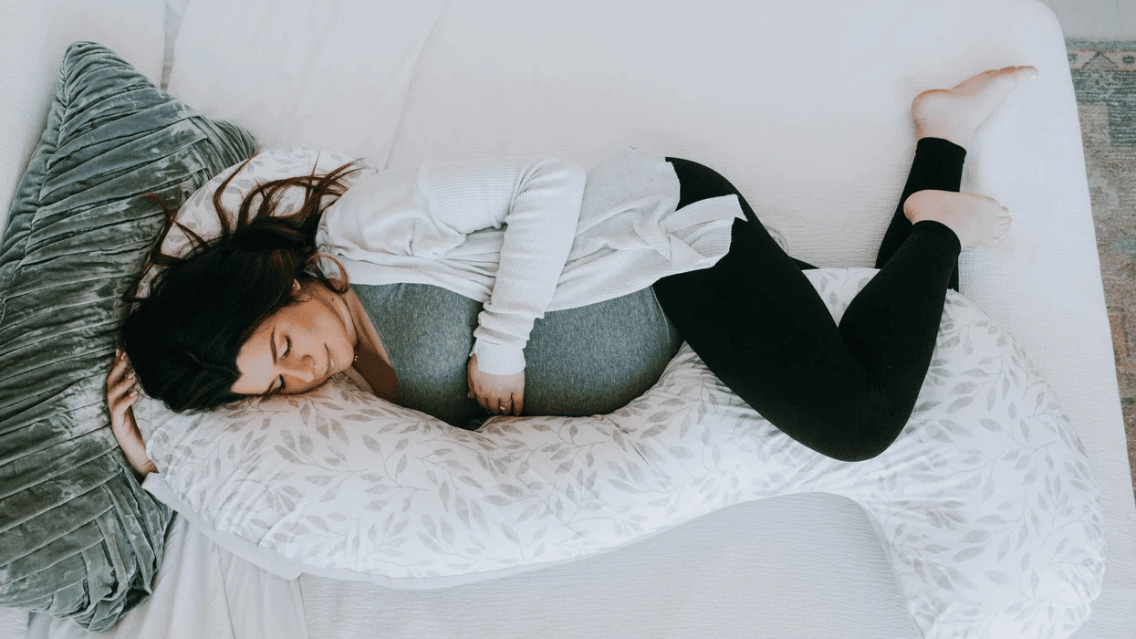 pregnant woman laying with a pregnancy pillow