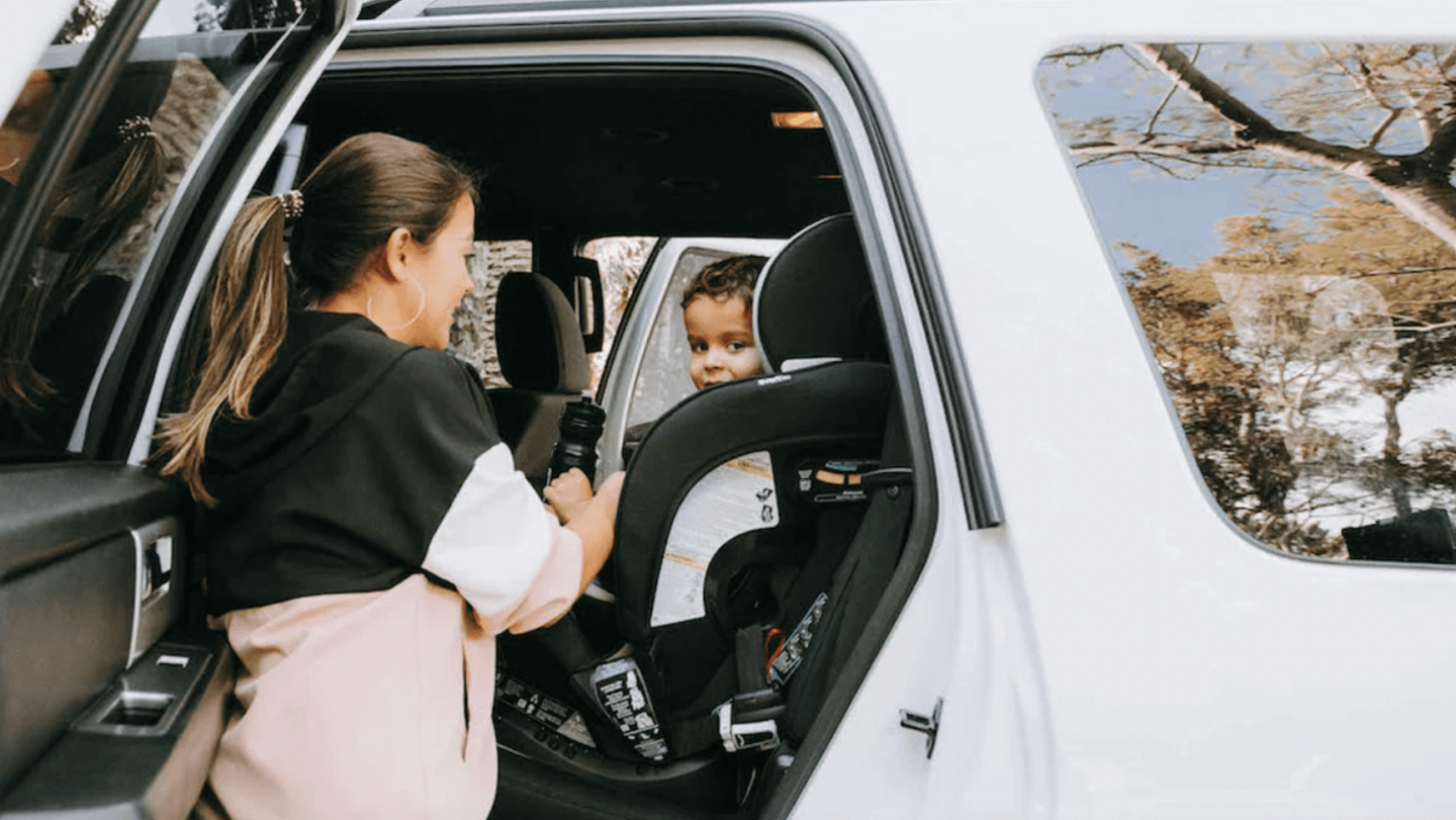 mom helping baby into a car seat