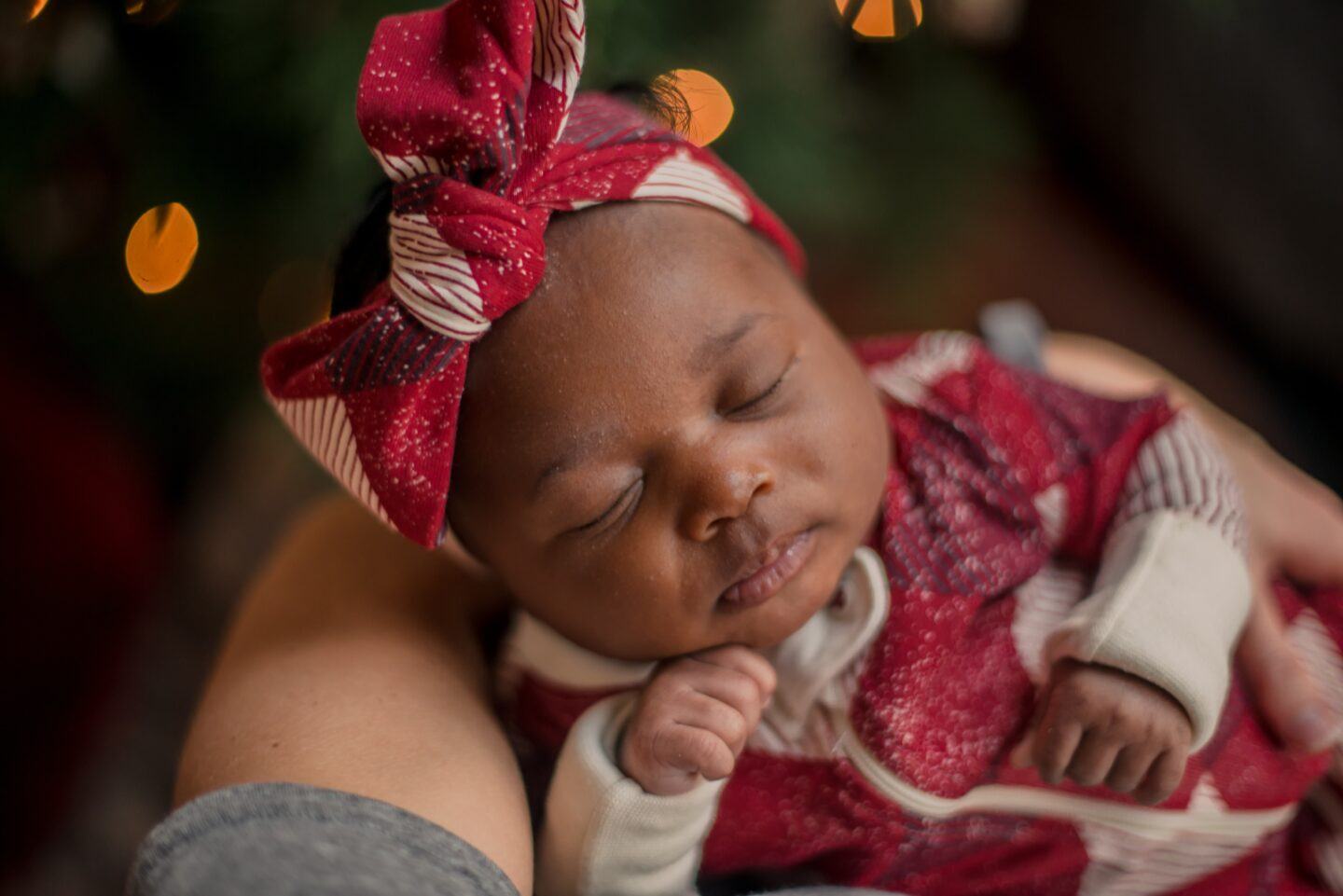 newborn baby sleeping by christmas tree