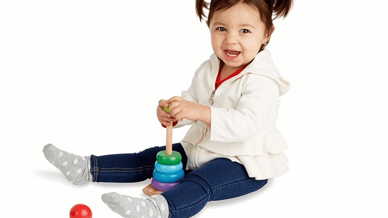 little girl playing with wooden rainbow stacking set