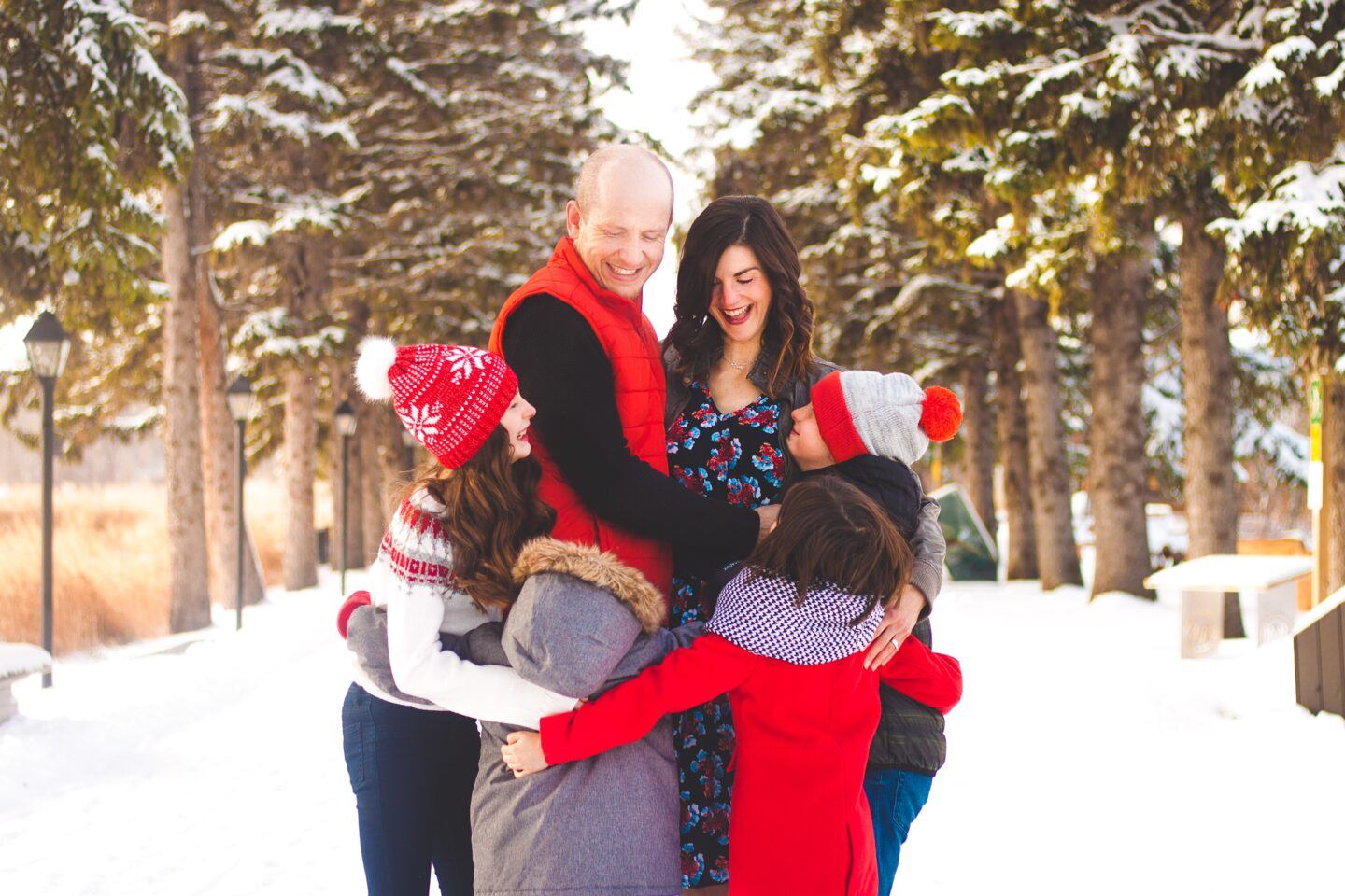 family hugging and kissing mom in the snow