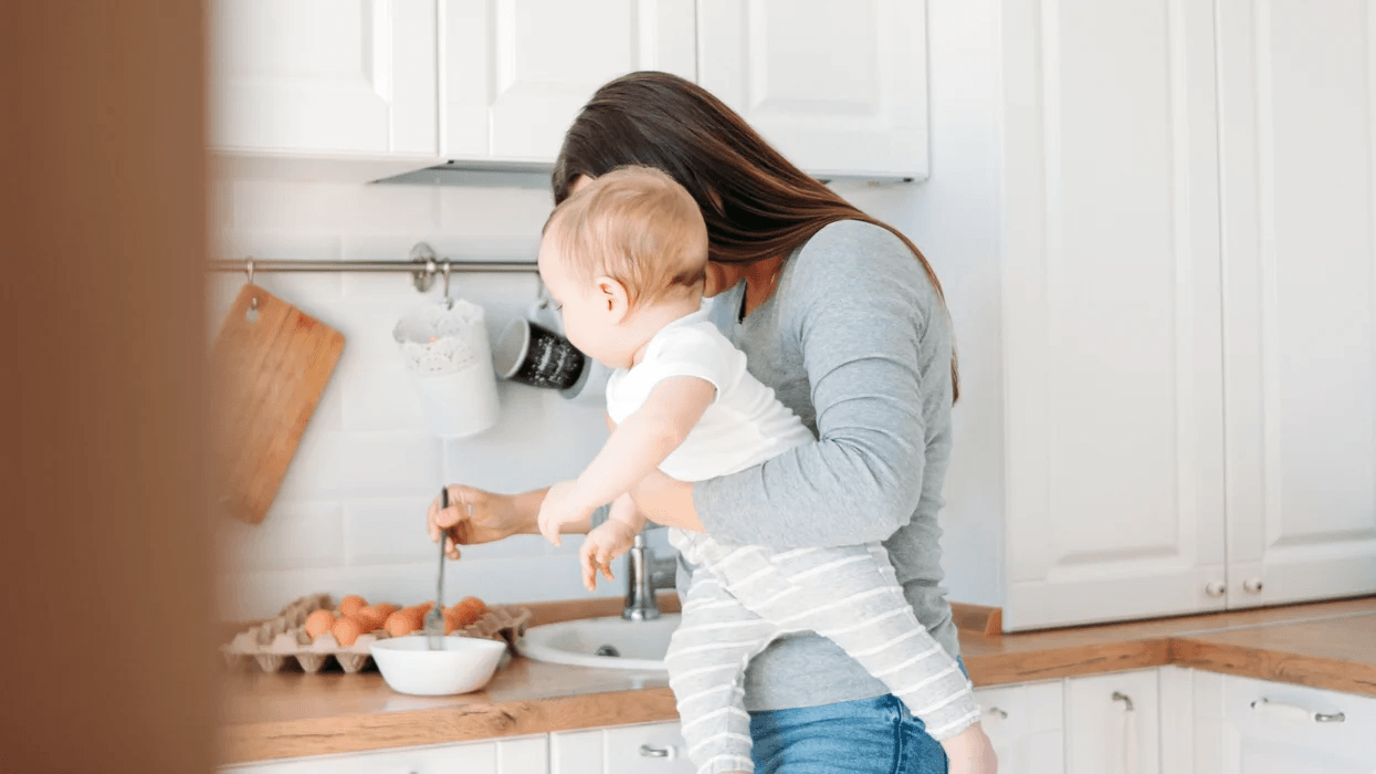 mom making dinner while holding baby