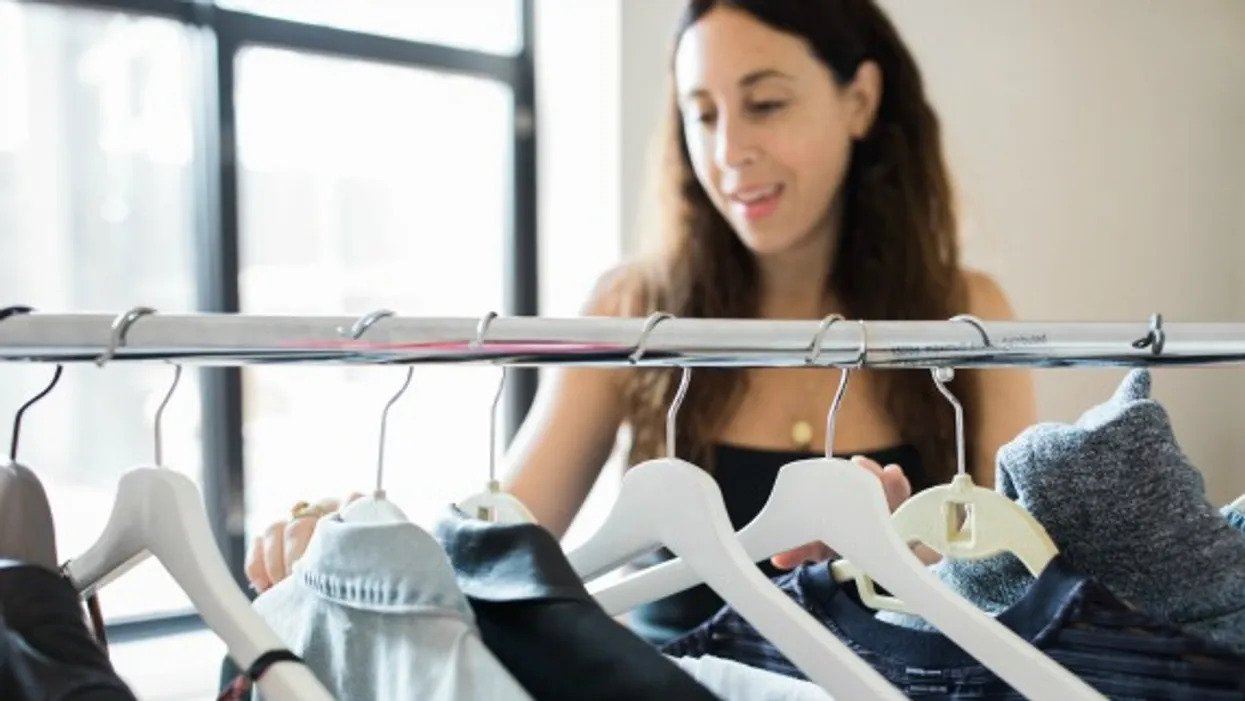 woman browsing clothes on rack - first trimester maternity clothes