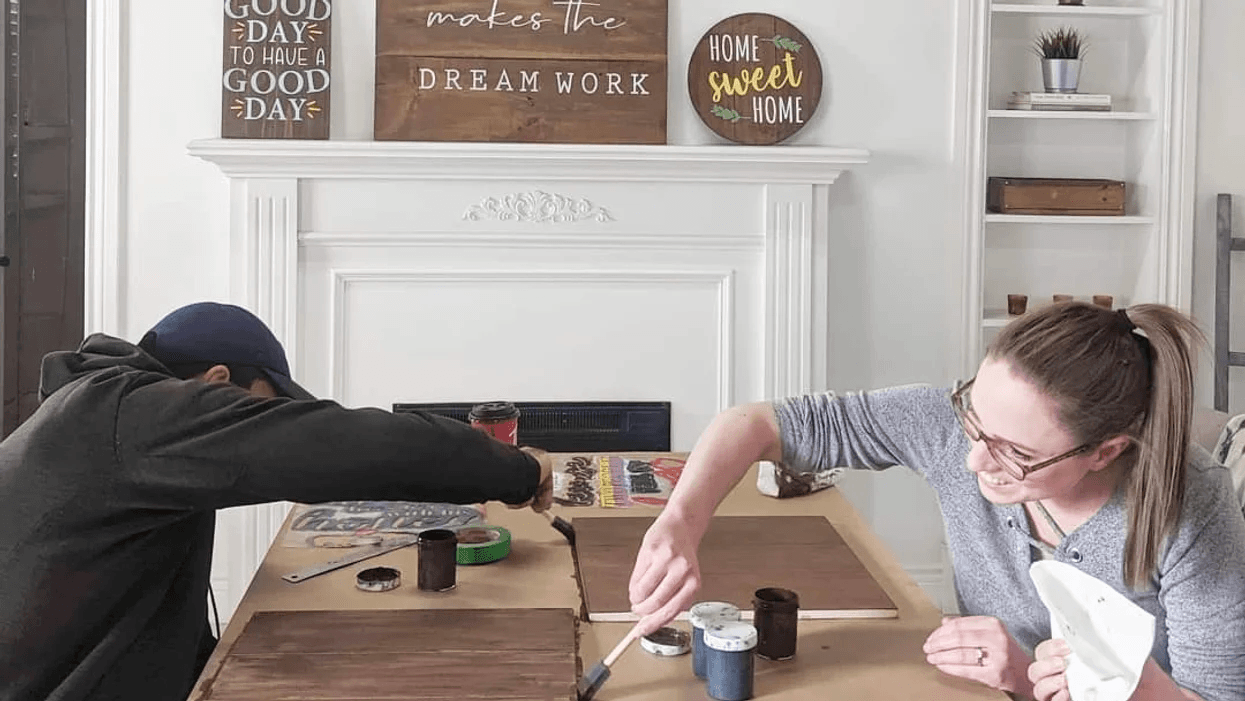 man and woman staining boards on cardboard