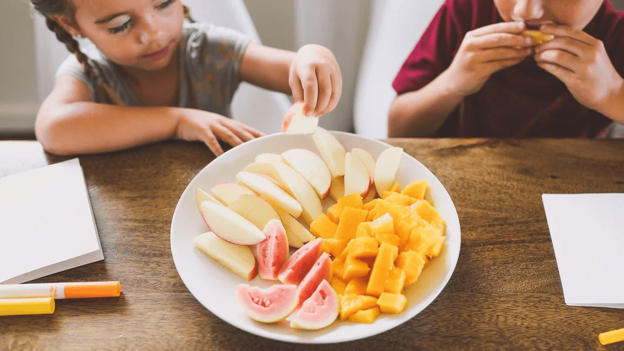 toddlers eating off a plate of snacks