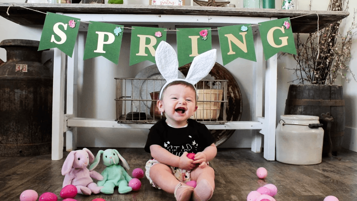 baby sitting in front of a spring sign