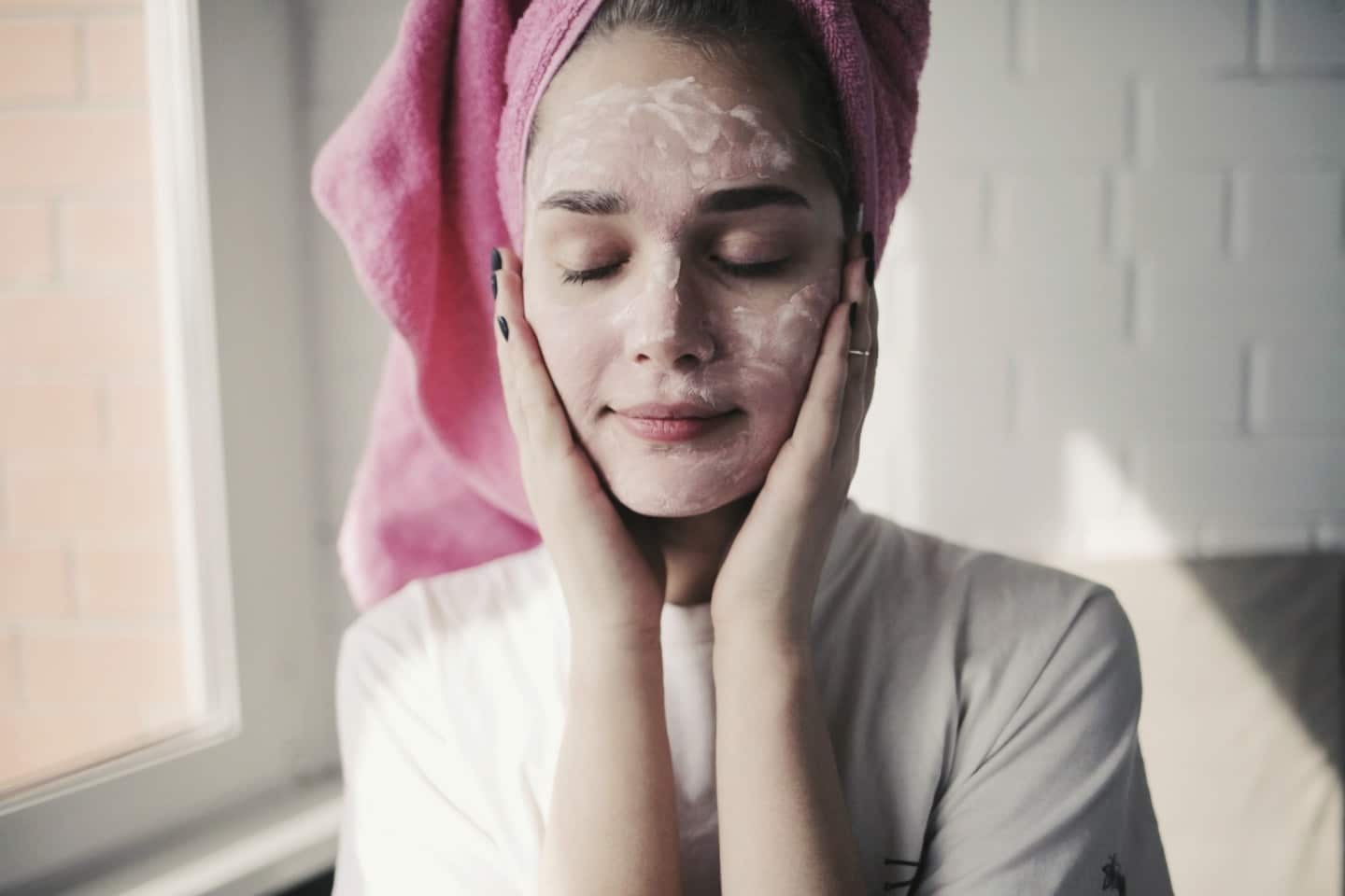 woman washing face with cleanser