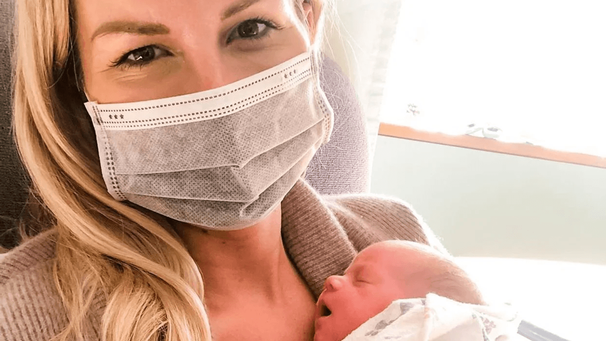 mom wearing a mask holding newborn baby