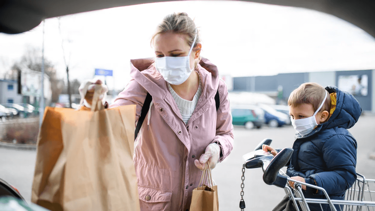 mom and son loading groceries wearing masks