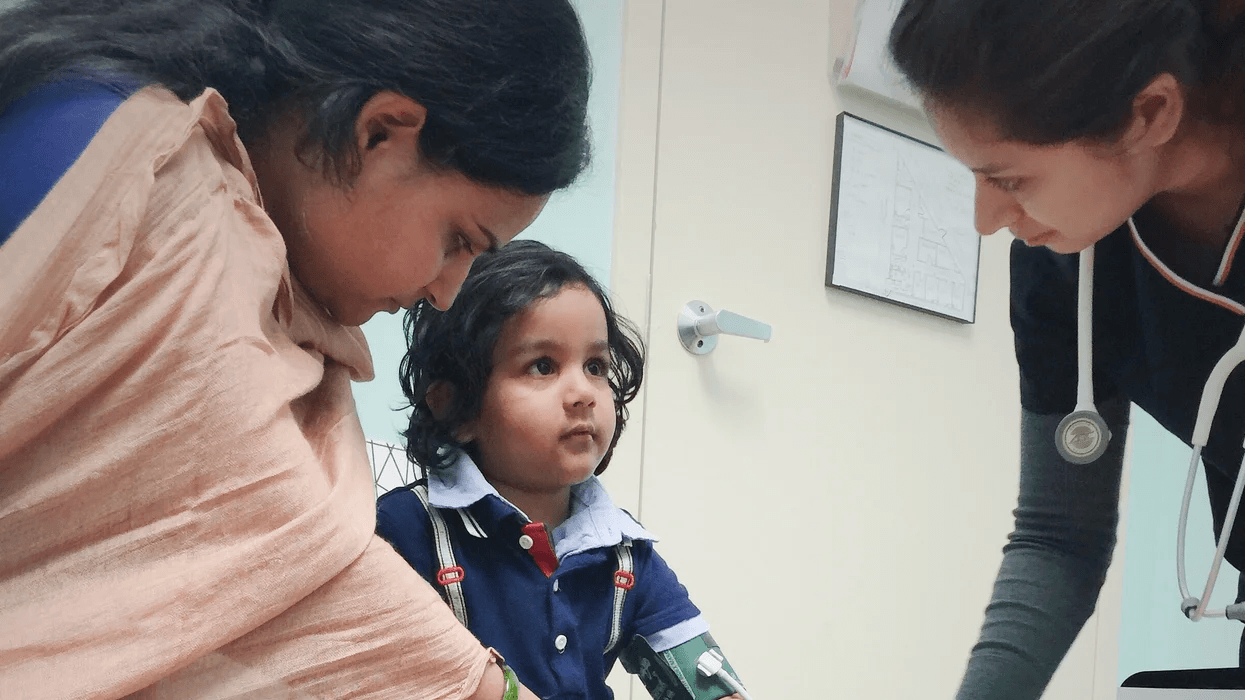 doctor checking out a toddler and his mom sitting beside him