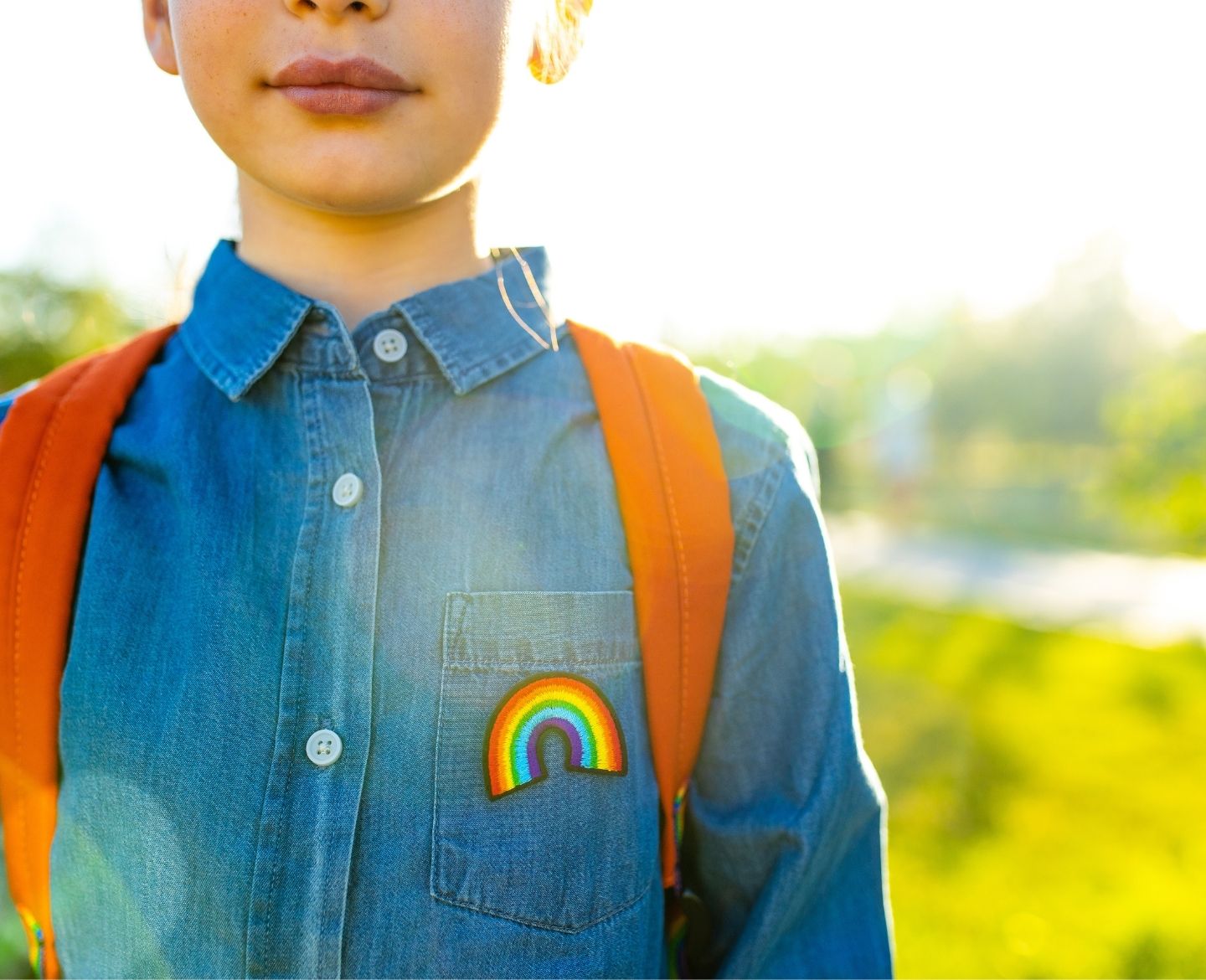 child with rainbow denim top