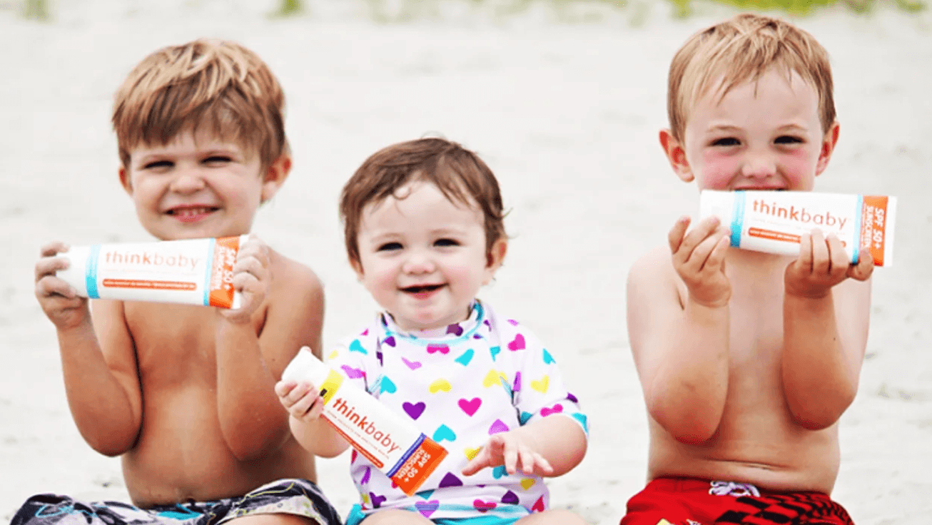 babies holding a tube of Thinkbaby sunscreen