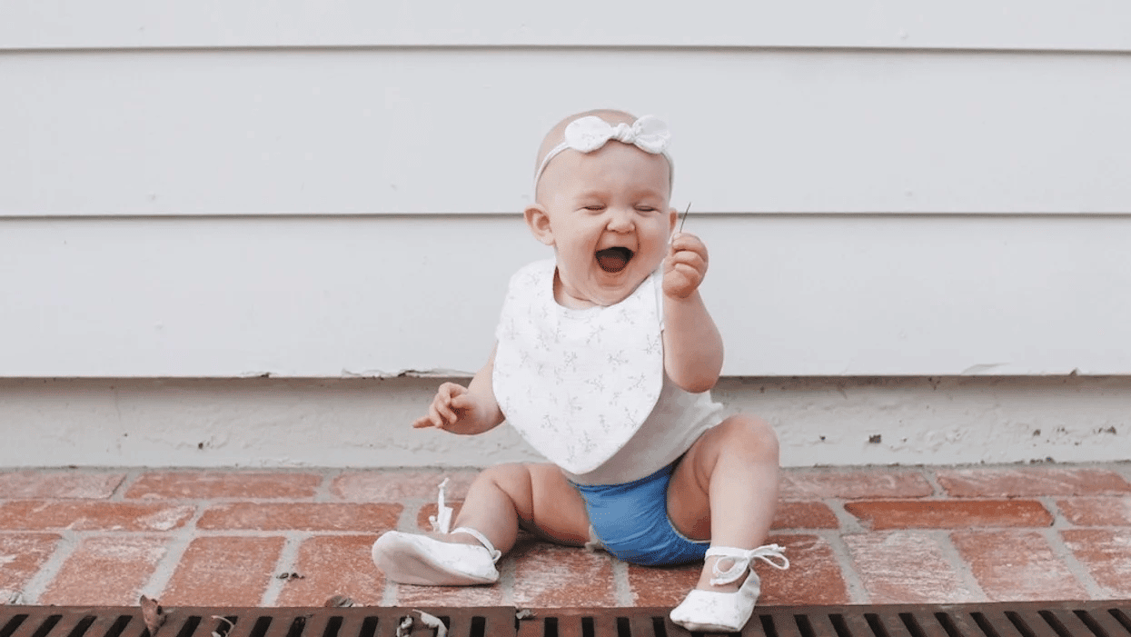 baby laughing at a piece of grass- july babies