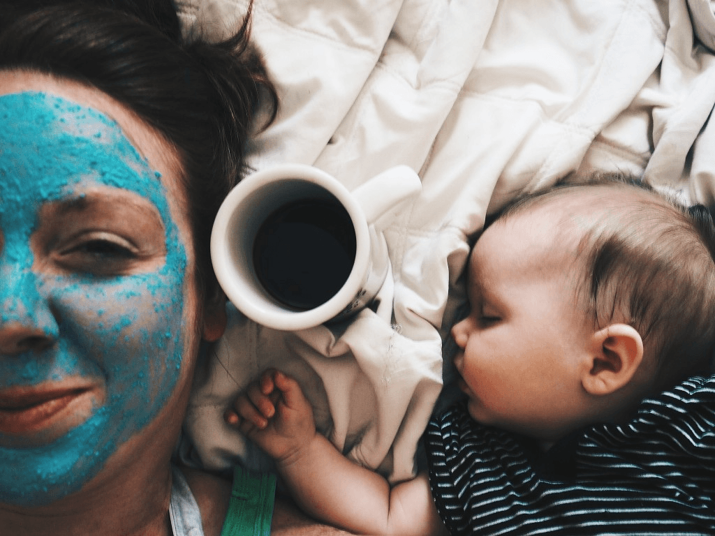 mom wearing a facemask and a new baby is sleeping beside her