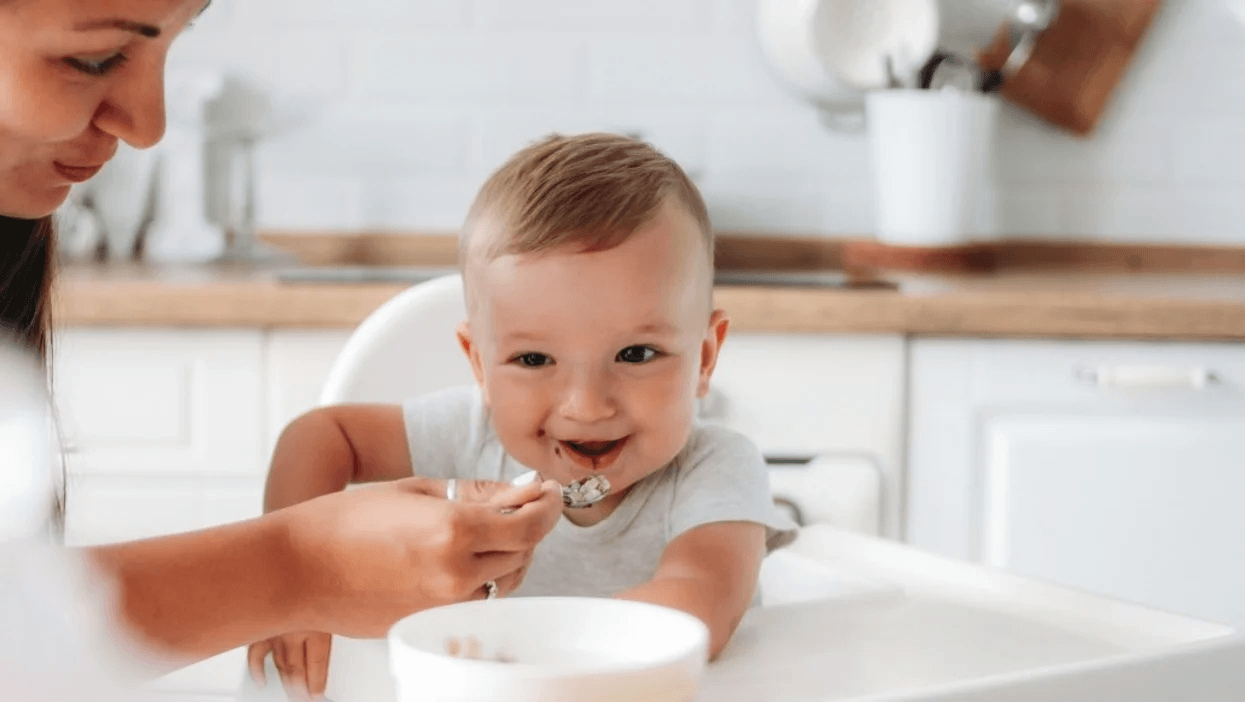 baby eating yogurt in a high chair