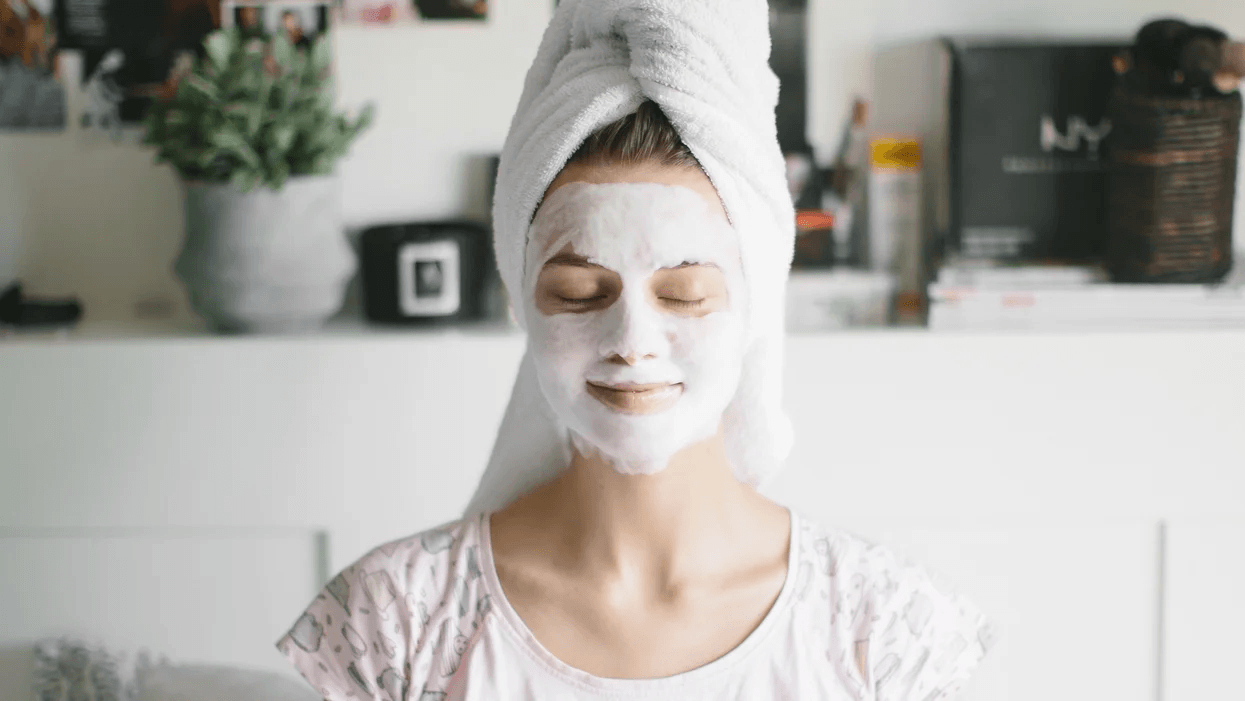 woman wearing a beauty mask with her hair in a towel