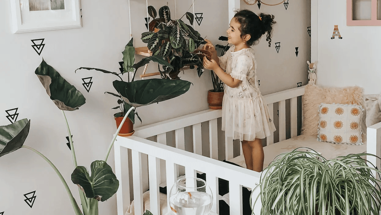 little girl playing with indoor plants in her nursery- plant decor