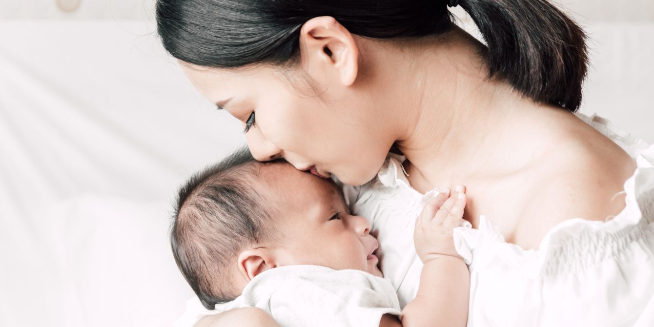 mom kissing newborn baby on the head