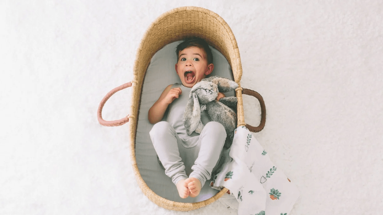 toddler laughing in a bassinet