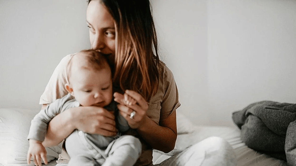 mom kissing newborn baby on top of her head