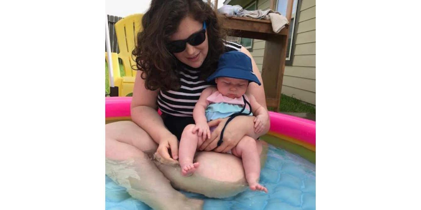 mom holding a baby in a pool - essay on becoming a first time parent during Covid-19