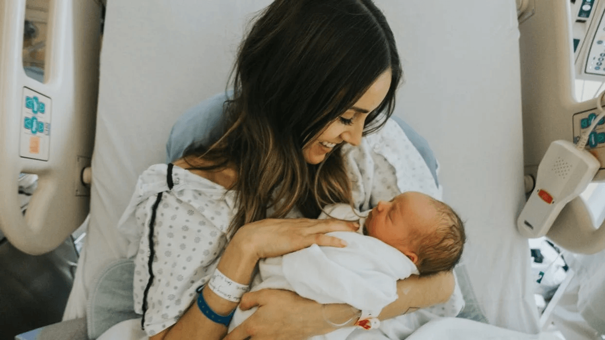 mom holding newborn baby in a hospital bed after birth