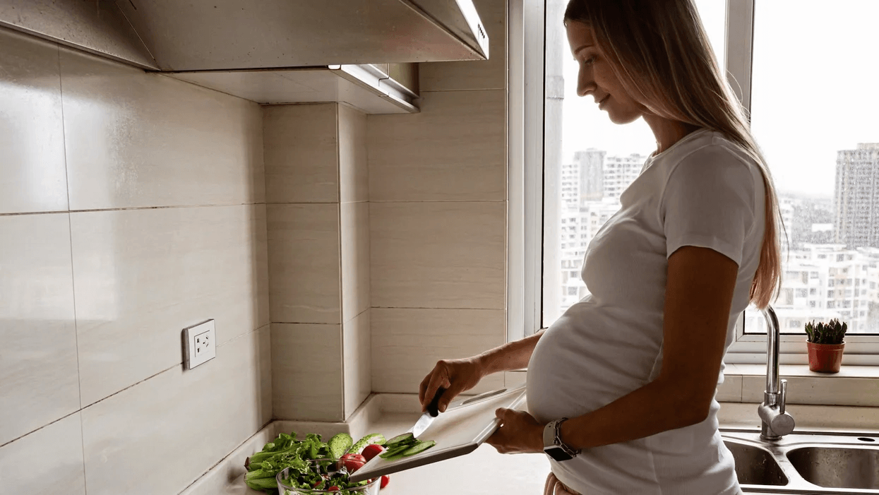 pregnant woman cooking with vegetables