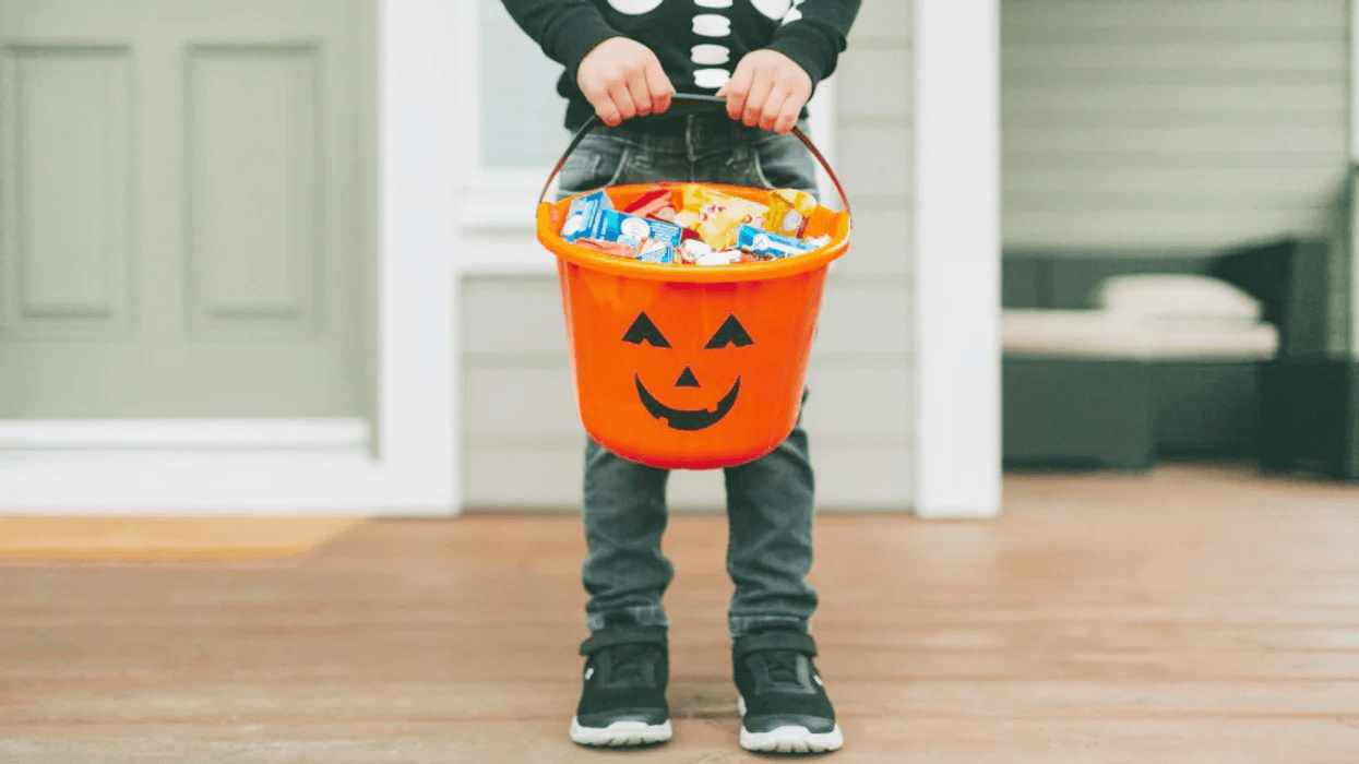 little boy holding a bucket of halloween candy