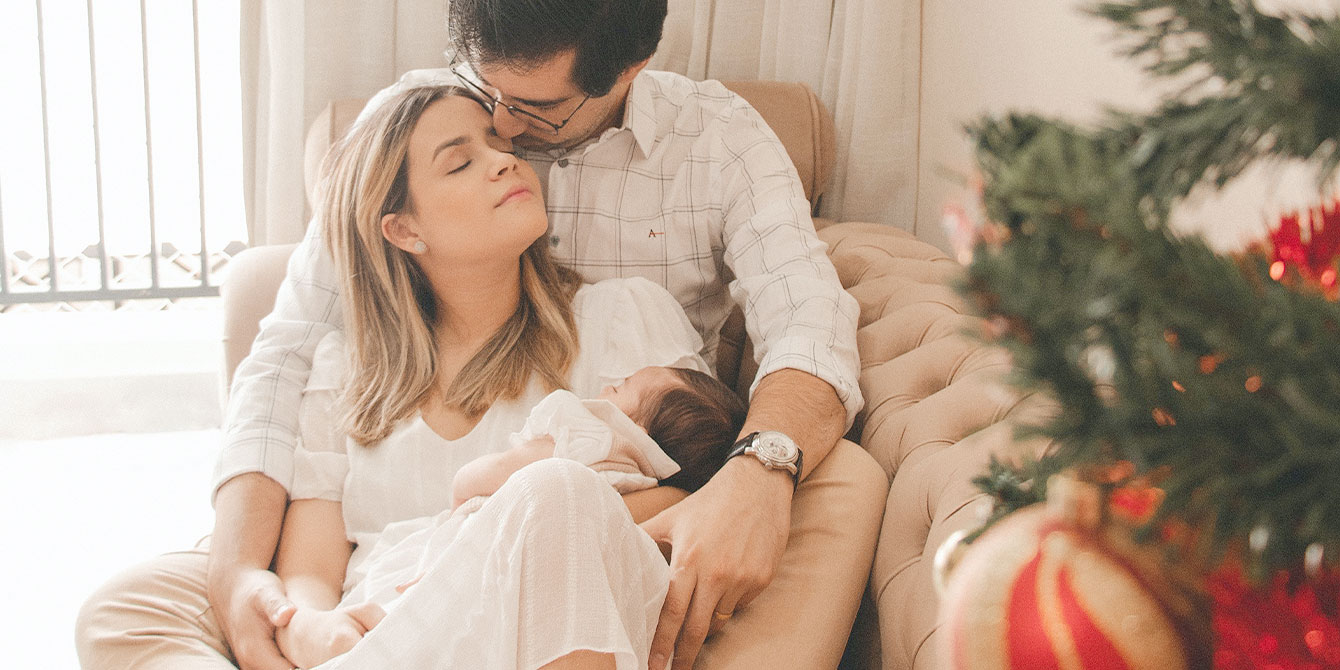 couple with newborn on the couch during christmas- rules for visiting newborns