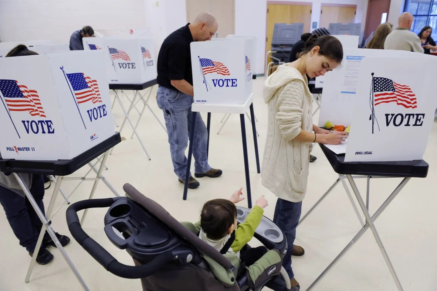 mom casting her vote with child in stroller next to her - can you bring your child to vote