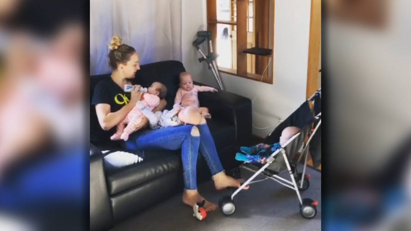 mom of quadruplets holding two babies and pushing on in a stroller