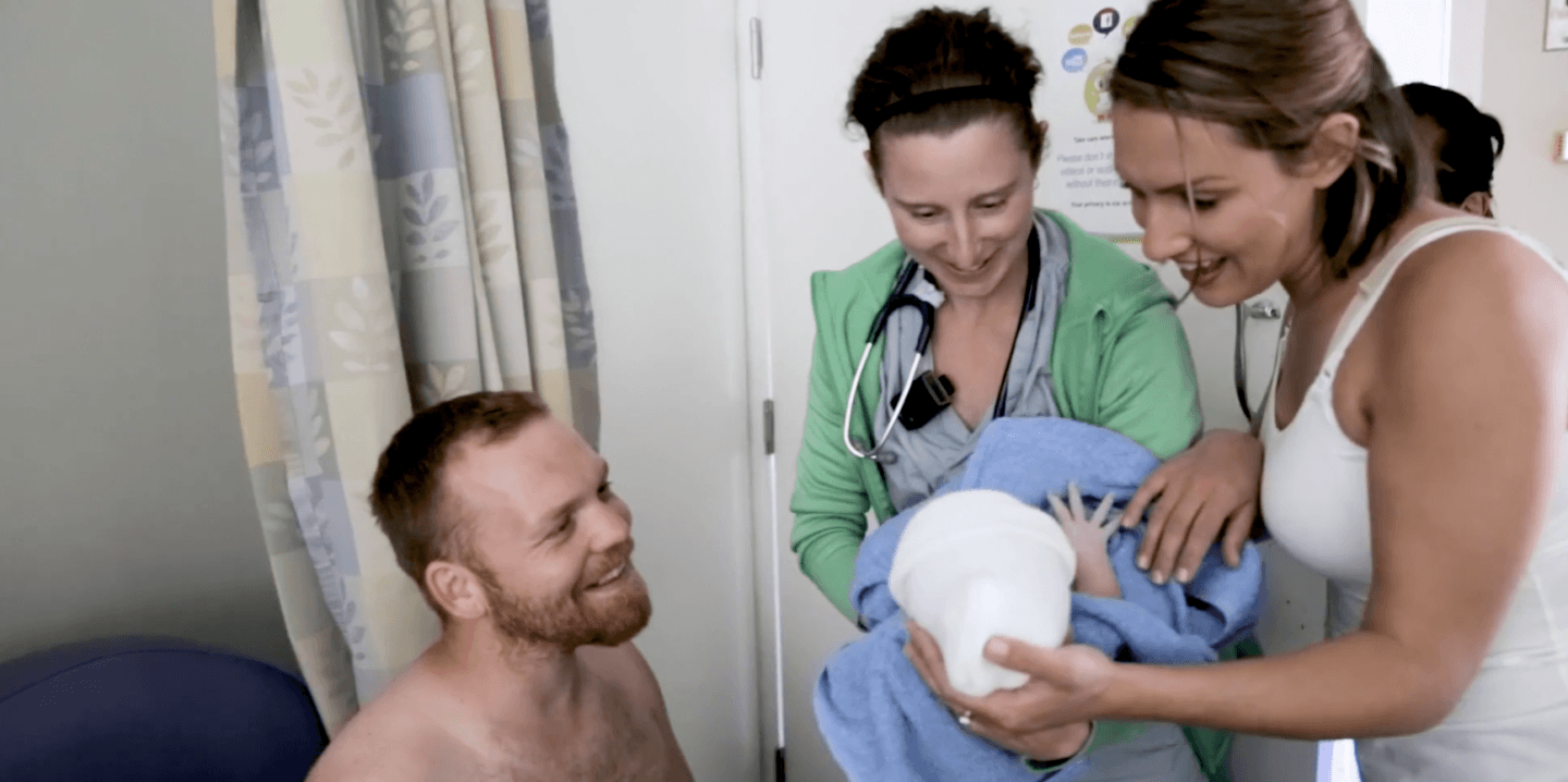 parents being handed baby in a hospital