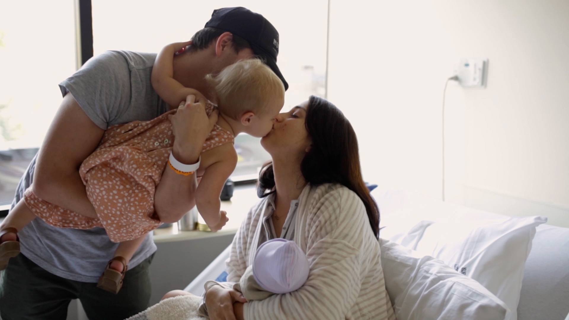 woman kissing baby while in delivery room