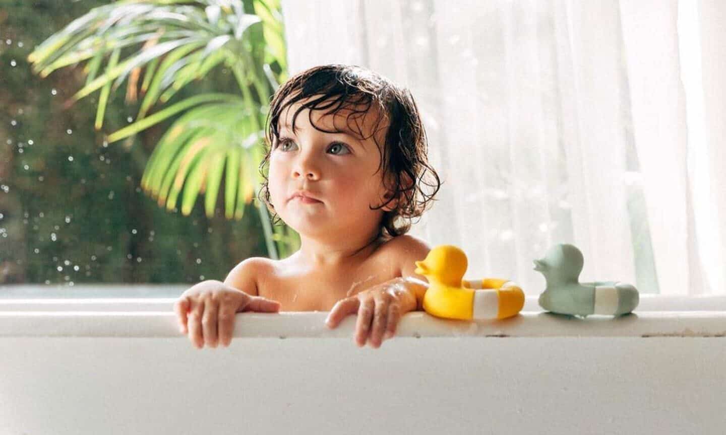 toddler in bathtub with bath toys