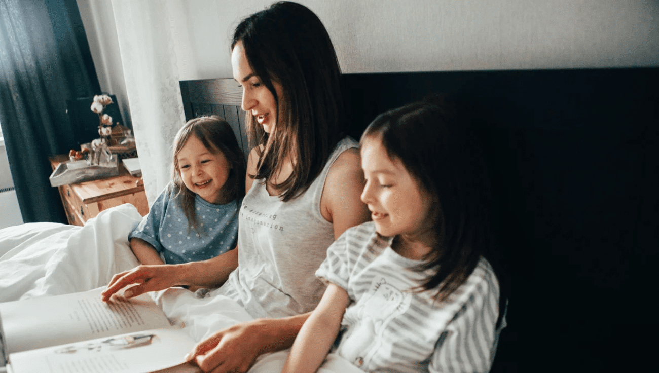 mom reading with two girls in bed- books about inspiring women