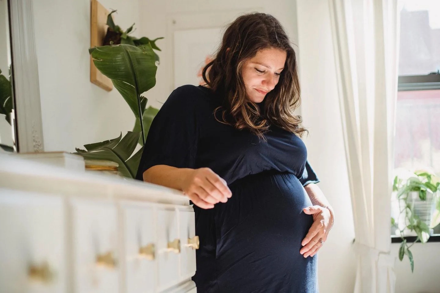 pregnant woman looking down and holding belly - breast growth in pregnancy