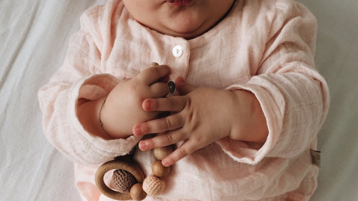 baby playing with wooden teething toy