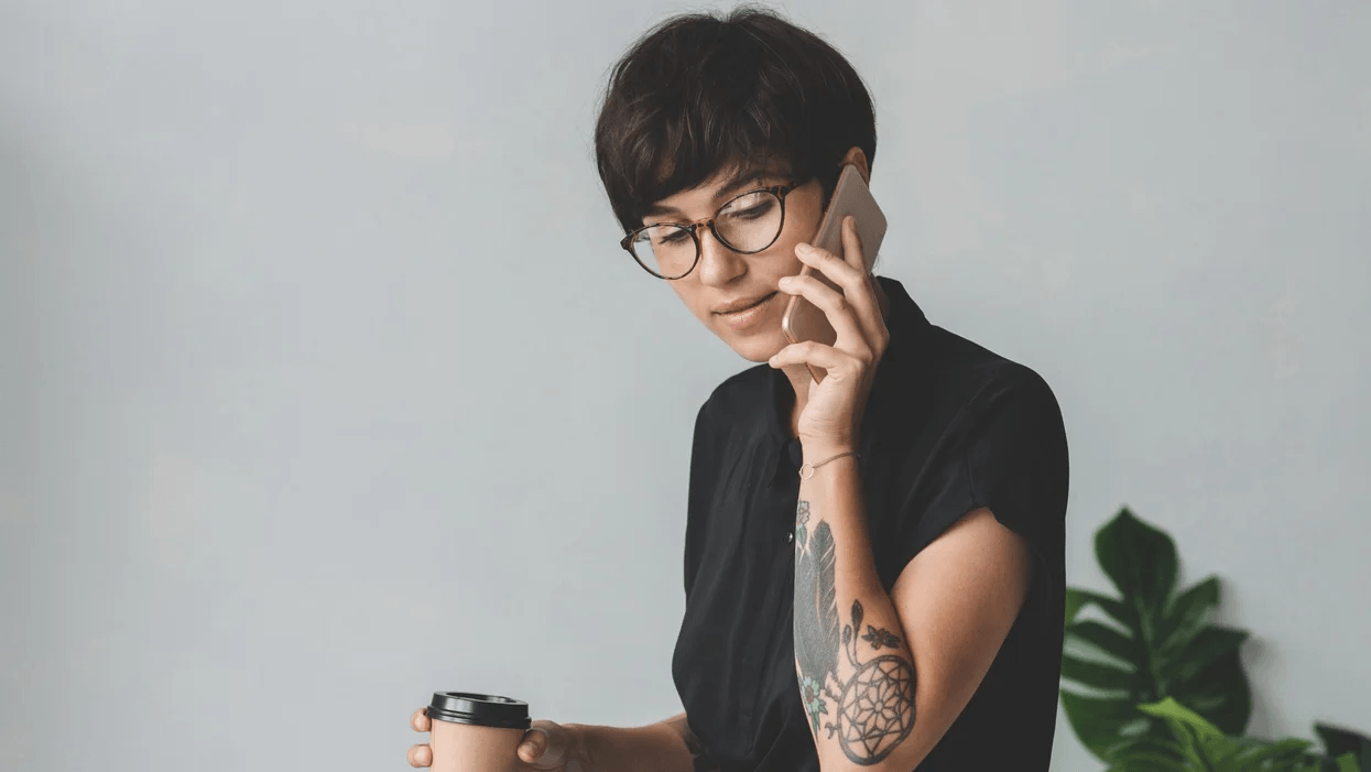 woman on the phone while holding a cup of coffee