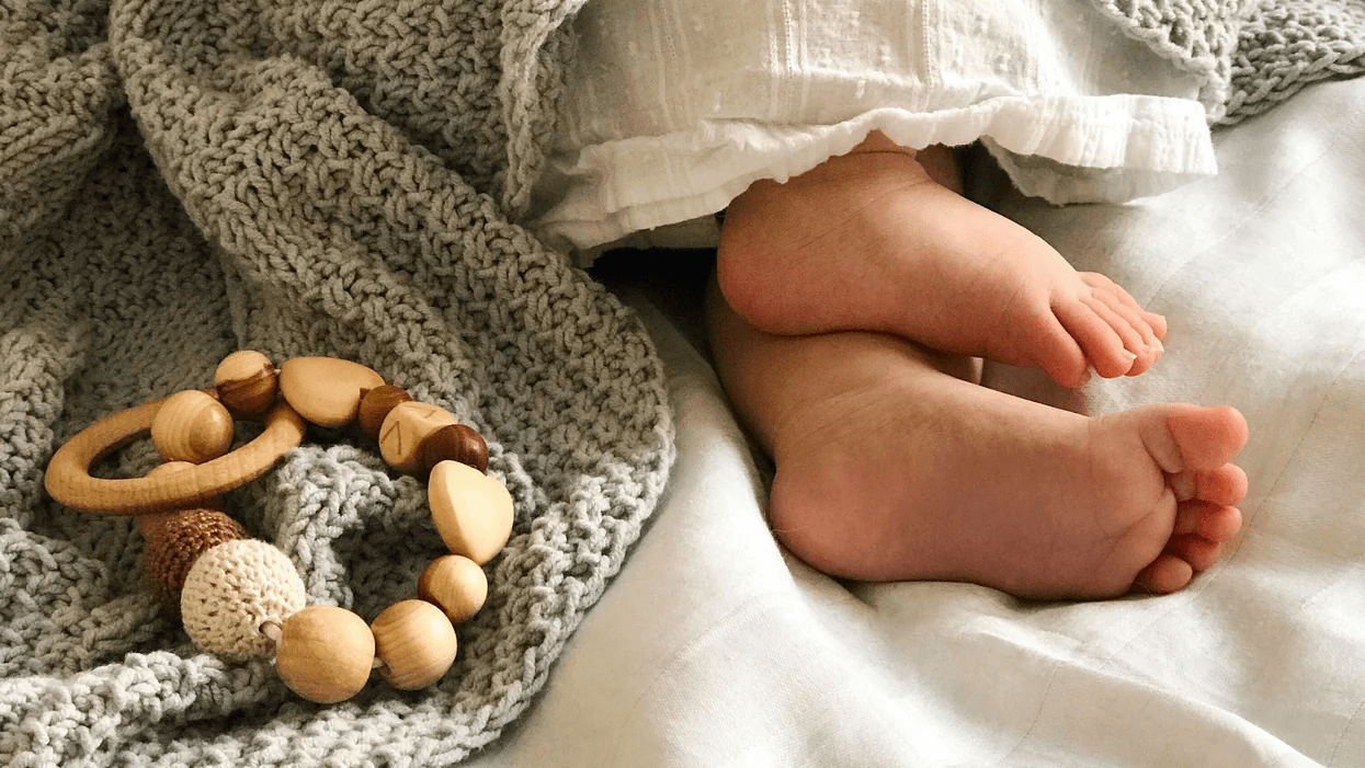 baby feet next to a montessori toy