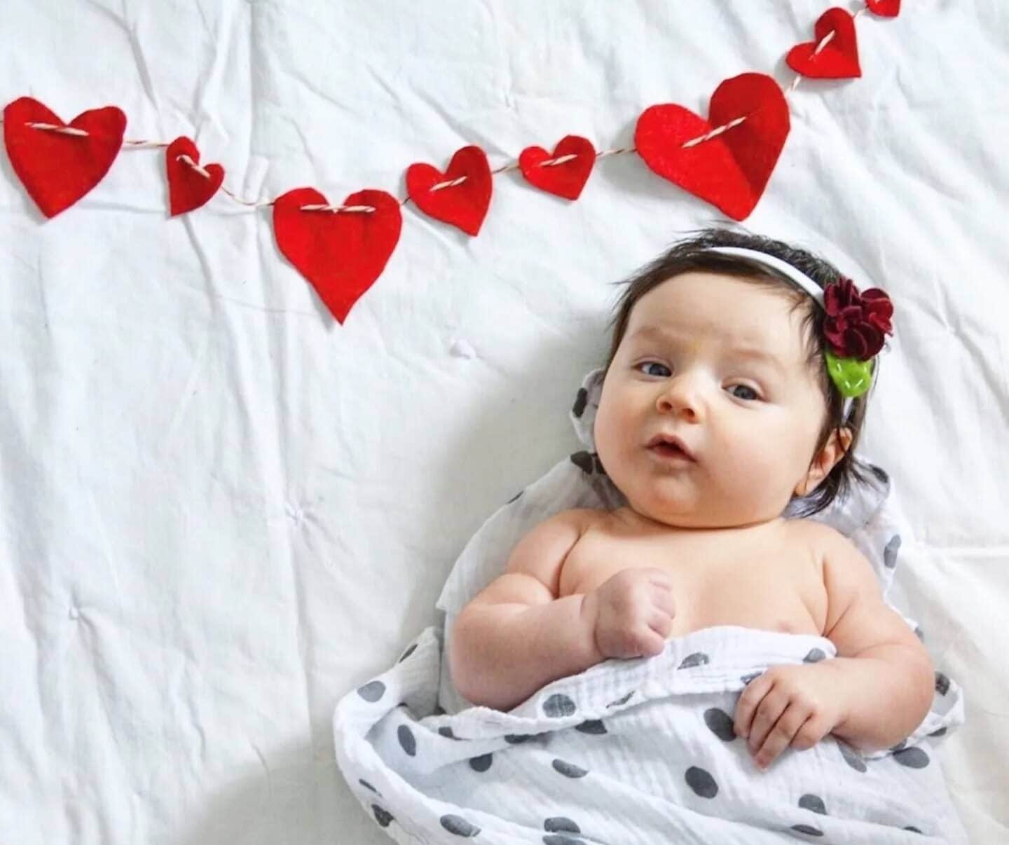 swaddled baby by a heart string- baby names that mean love