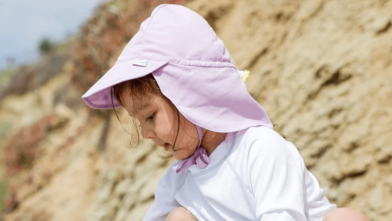 baby wearing a sun hat playing on the beach