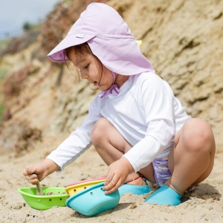 little girl wearing a lilac play hat on the beach
