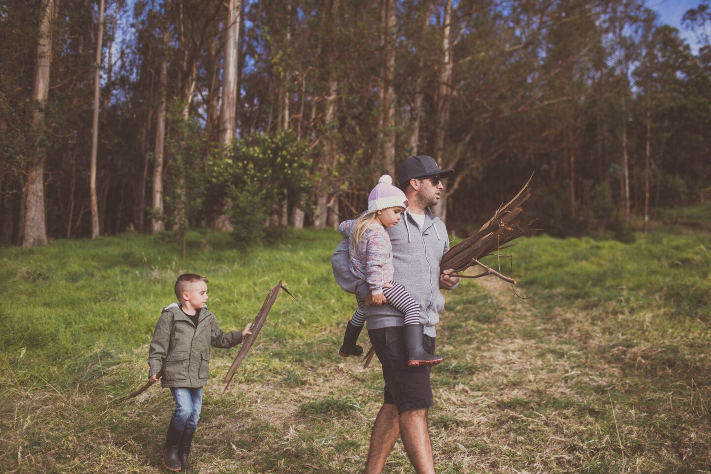 dad carrying sticks and kids outside