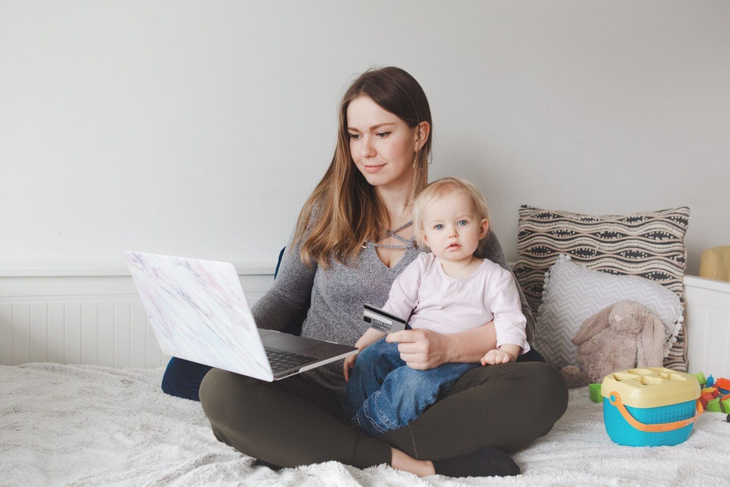 mom online shopping while daughter sits on her lap