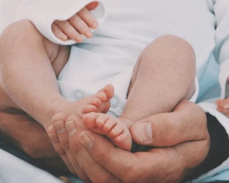 baby feet in dads hands Motherly