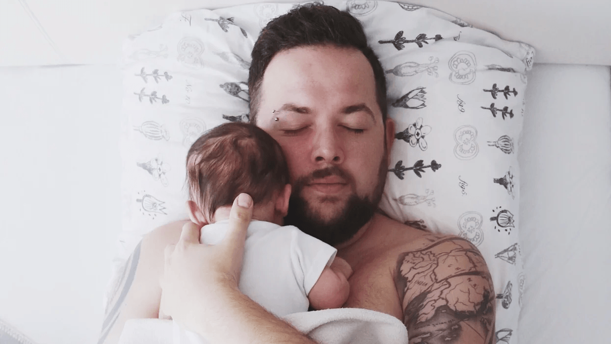 dad snuggling baby in bed