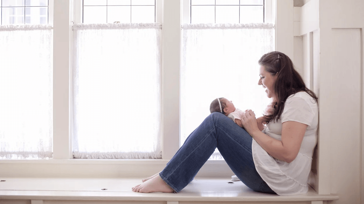 mom playing with newborn in a reading nook